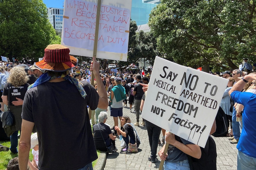 Protesters stand with a sign that reads: "say no to medical apartheid"