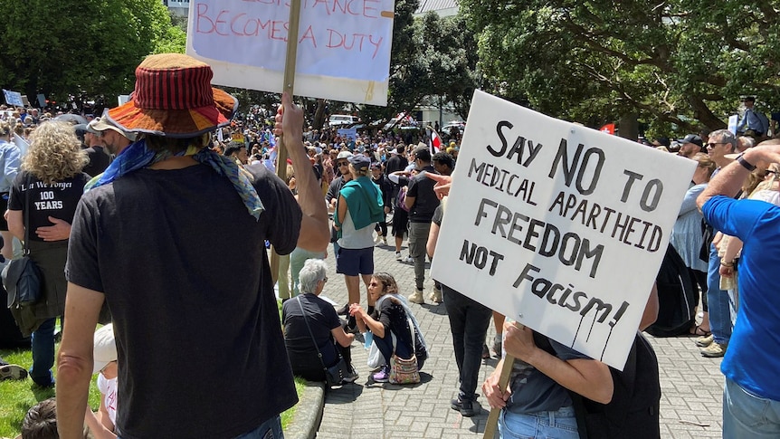 Protesters stand with a sign that reads: "say no to medical apartheid"