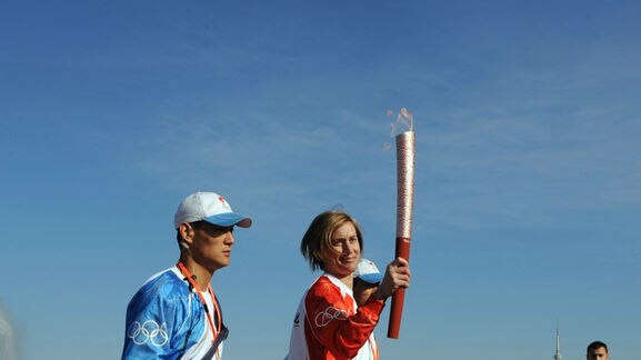 Megan Marcks carries the Olympic flame in Canberra flanked by Chinese flame attendants