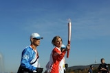 Megan Marcks carries the Olympic flame in Canberra flanked by Chinese flame attendants