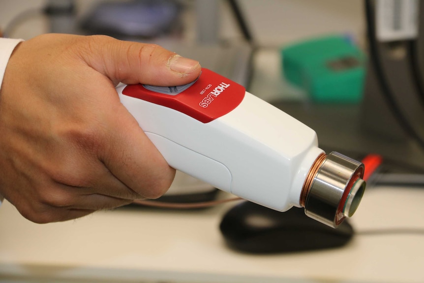 Hand holding a portable ultrasound device aimed at improving the accuracy of breast cancer surgery.