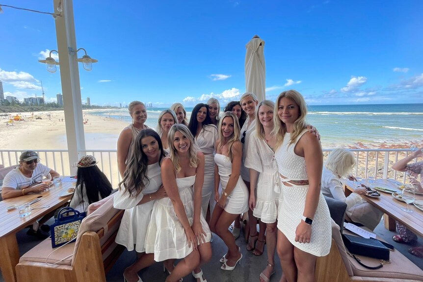 Un rassemblement d'une dizaine de femmes, toutes vêtues de blanc, avec une plage en toile de fond