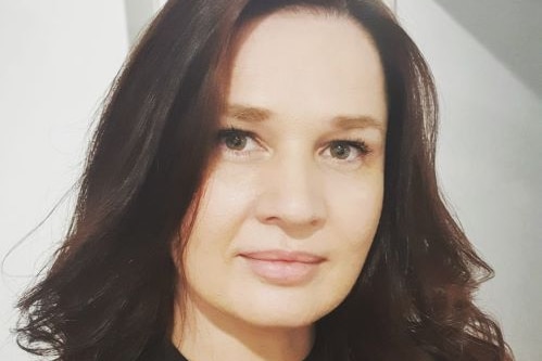 Head shot of woman with brown hair hair staring straight ahead.