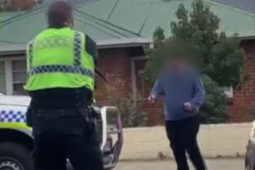 Police confront an armed man in a street north of Hobart.