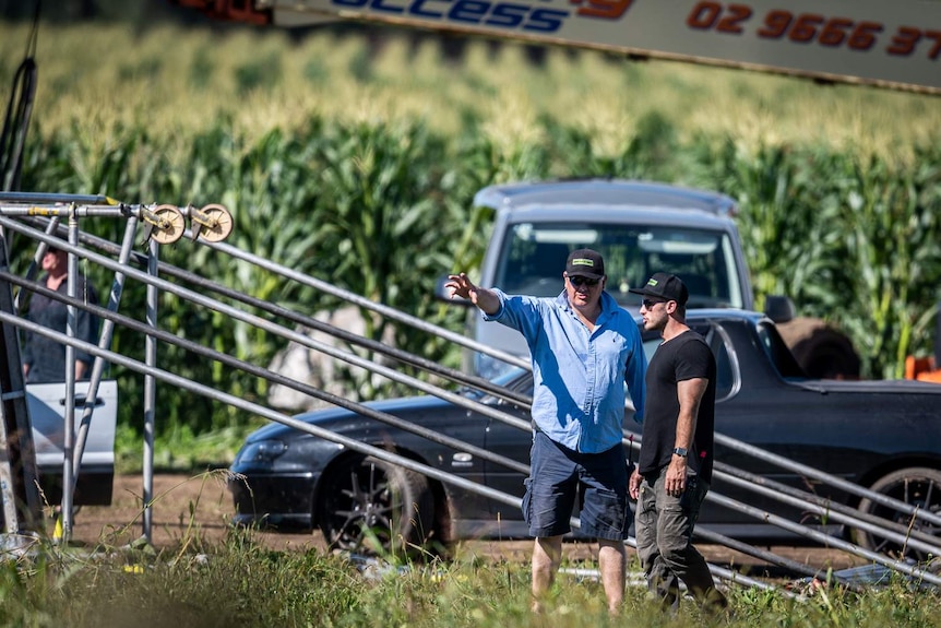 Vehicles and production crew are seen in a cornfield.