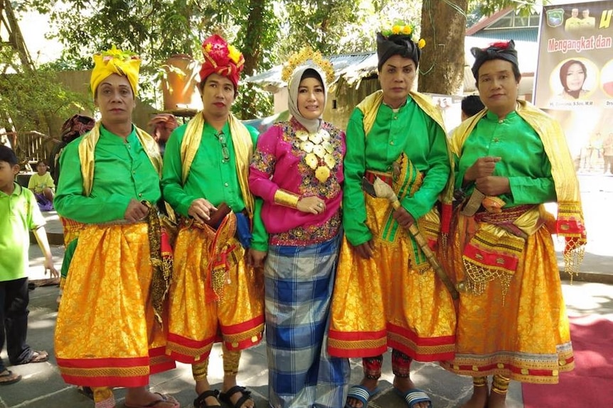 Four colourfully dressed bissu stand in a row with cultural worker Dasriana in the centre.