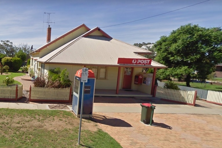 A Google Street View image of a country town post office, with a public phone box outside.