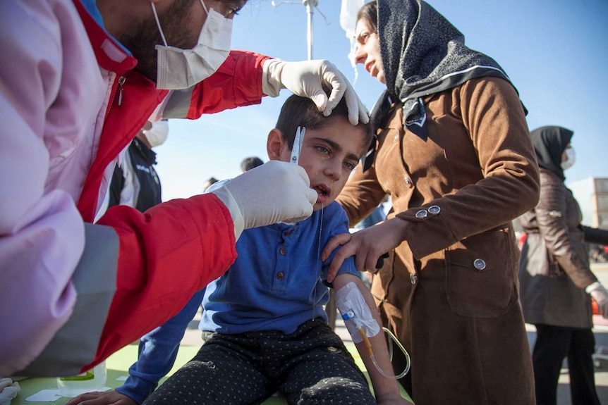 A doctor treats a wound on a boy's face.