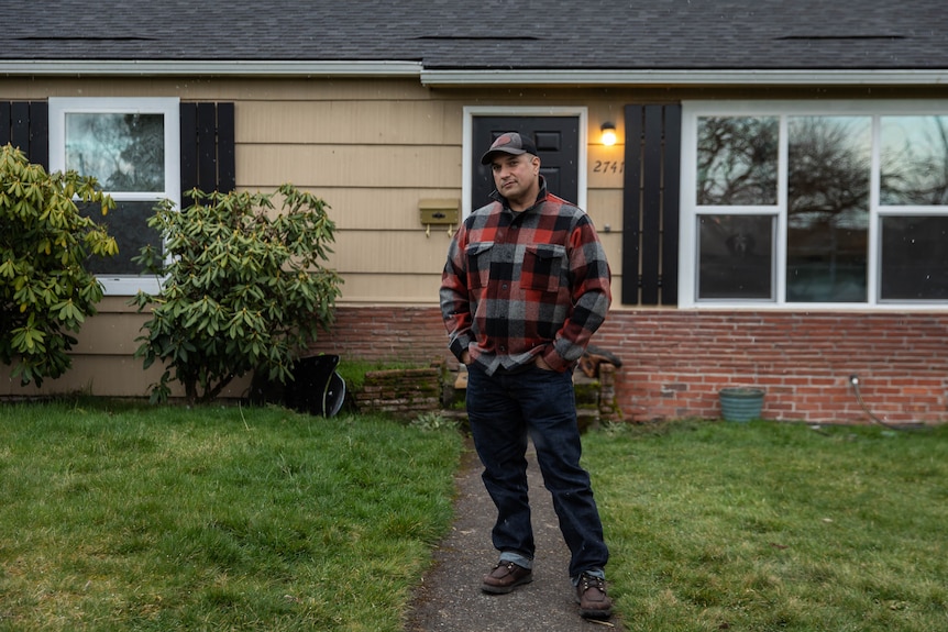 A man stands in front of a house.