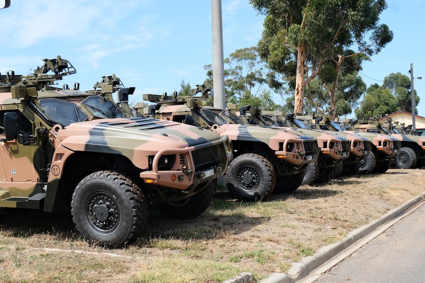 Hawkei protective vehicles in camoflague sit on a lawn