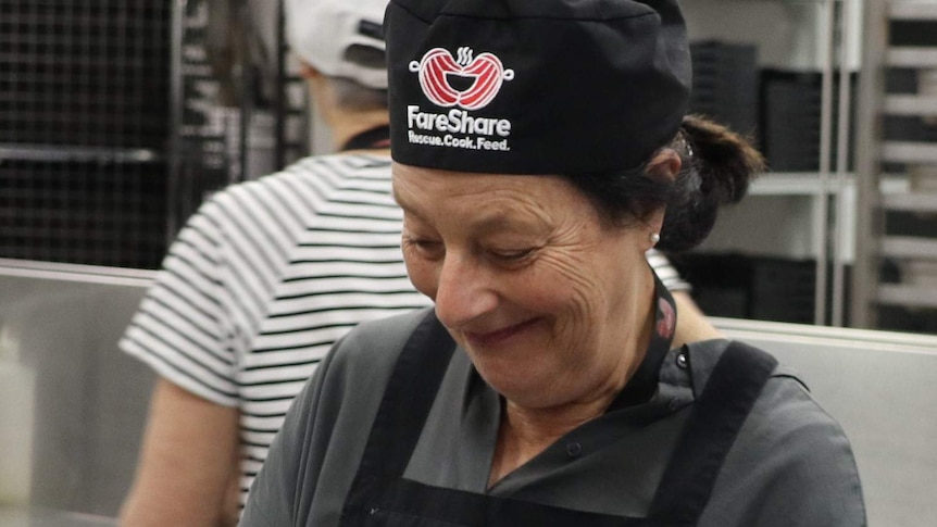 Sandy Dudakov wearing a FareShare apron and hat chopping mushrooms