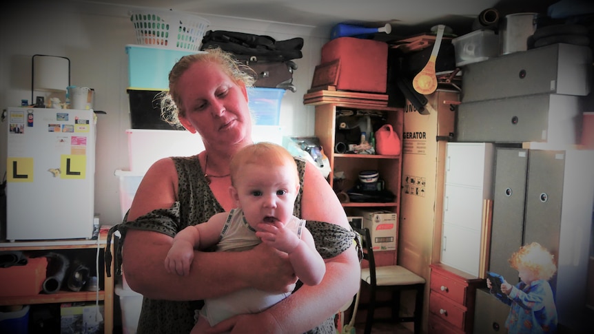 woman holding a baby with kitchen behind