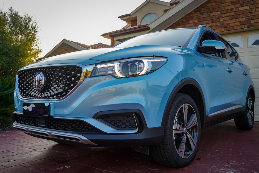 Un SUV azul se encuentra en una entrada suburbana