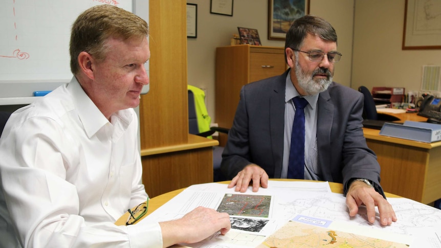 Curious Canberran Ben Chapman looks through early plans for Kambah with ACT Surveyor-General Jeff Brown.