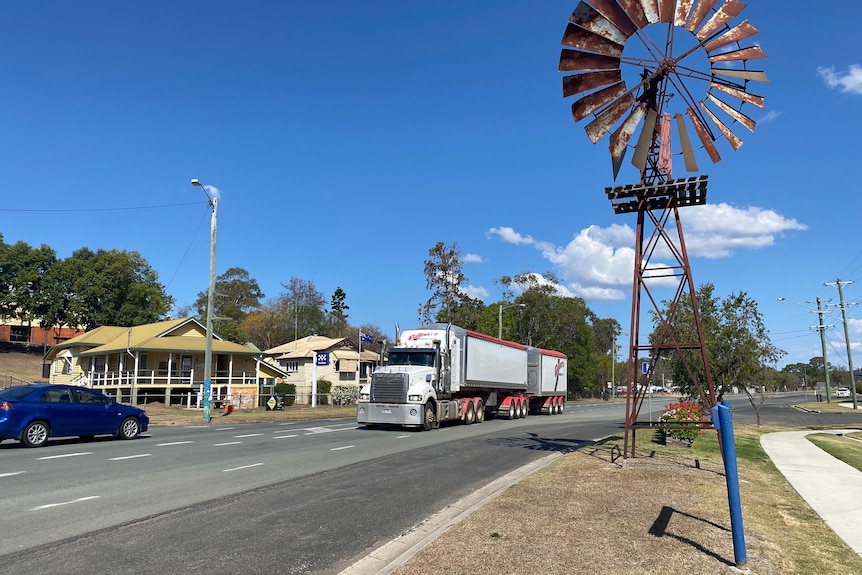 A truck and car driving past a windmill