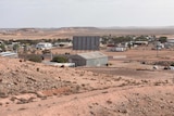 A few houses and buildings surrounded by red dirt in an outback landscape