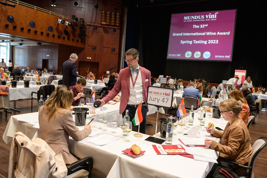 a big room with tables and people at tables tasting wine 