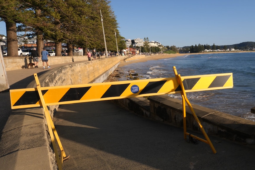 A yellow sign blocking access to a broken ramp that leads to the sand