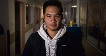 A mid-shot of Terry Vo standing in the corridor of Princess Margaret Hospital posing for a photo wearing a hoodie and jacket.