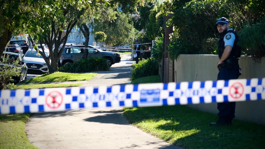 Police on suburban street with blue and white tape cordoning off the area.