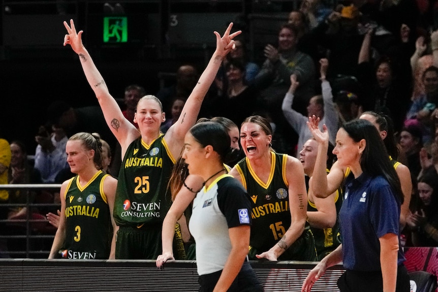 Opals basketballer Lauren Jackson smiles and raises her arms out in celebration as another Australian player shouts in joy.