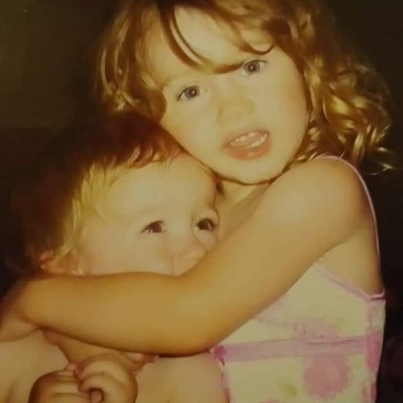 Lachlan and Hayleigh hug as young children, smiling.
