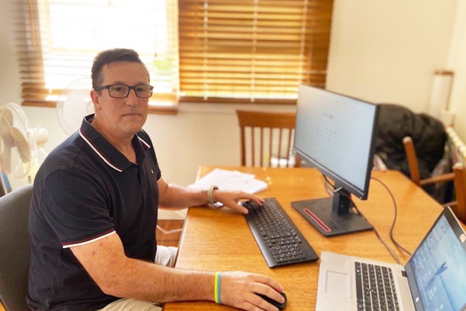 Chris Stoker sitting at a computer in his house.