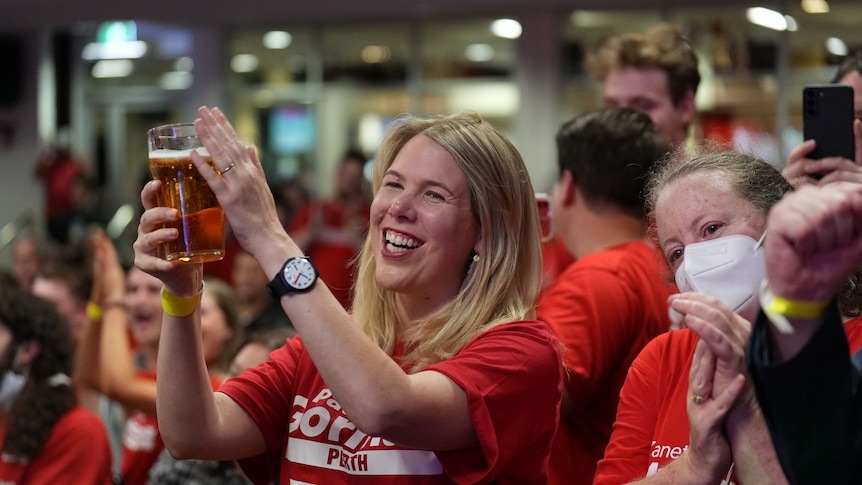 A woman holds a beer aloft at an ALP celebration on election night.