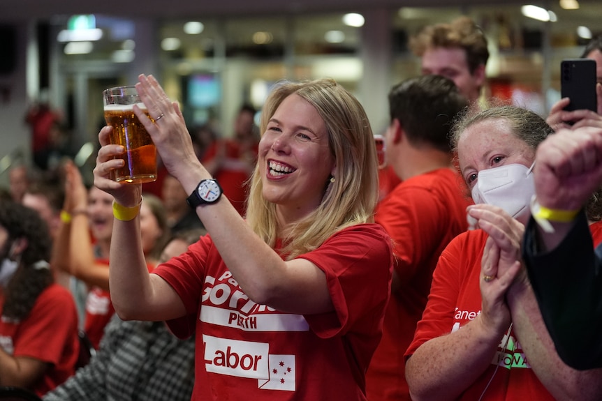 A woman holds a beer aloft at an ALP celebration on election night.