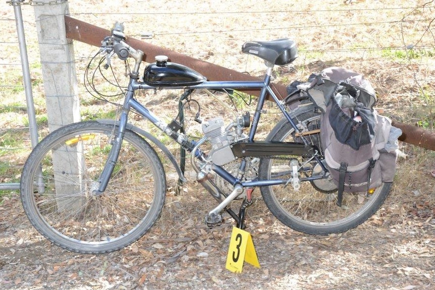 Kelvin Tennant's motorised bike sitting beside a fence.