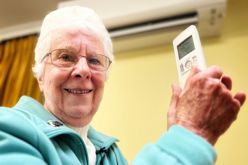 Heather smiles holding an aircon remote