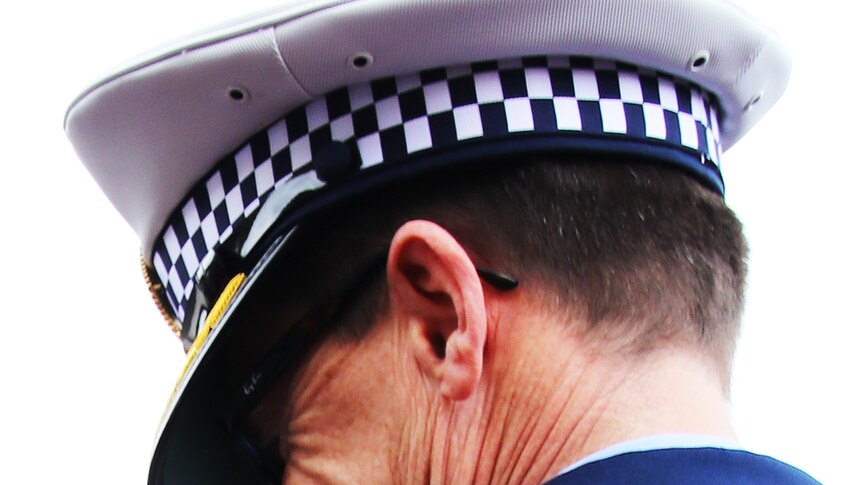 A man wearing a Tasmania Police hat pictured from behind, his face obscured by the shadow of the hat.