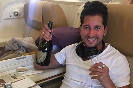 A man smiles as he holds a champagne bottle.