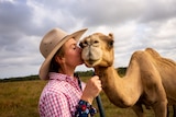 Photo of a woman kissing a camel.