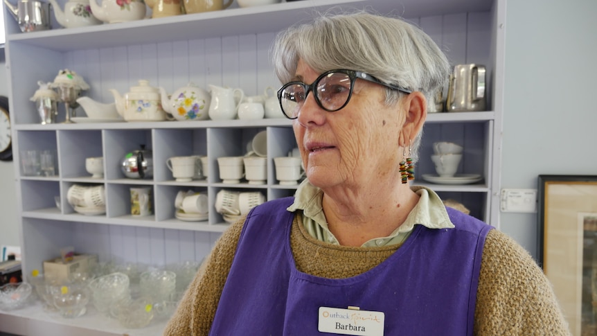 Barb Talbot stands in front of shelves of crockery