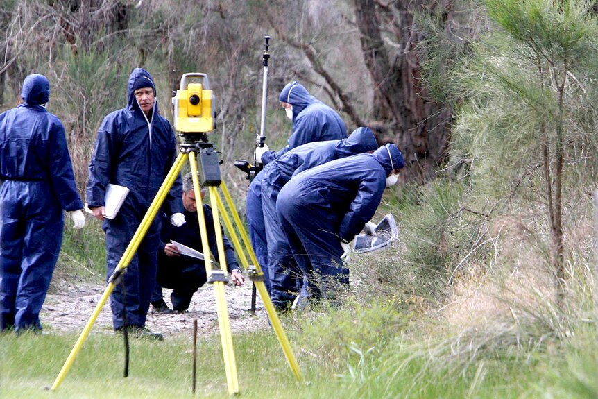 Police forensics officers in blue jumpsuits inspect an area of bush in Kings Park.
