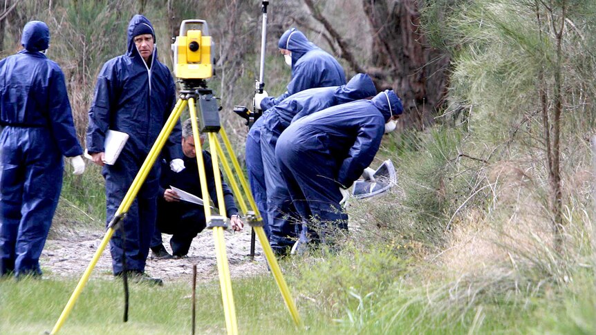Police forensics officers in blue jumpsuits inspect an area of bush in Kings Park.