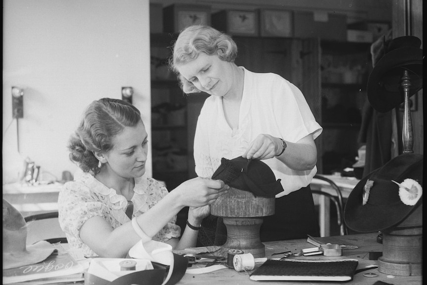 Two women examine a hat during the factory's heyday.