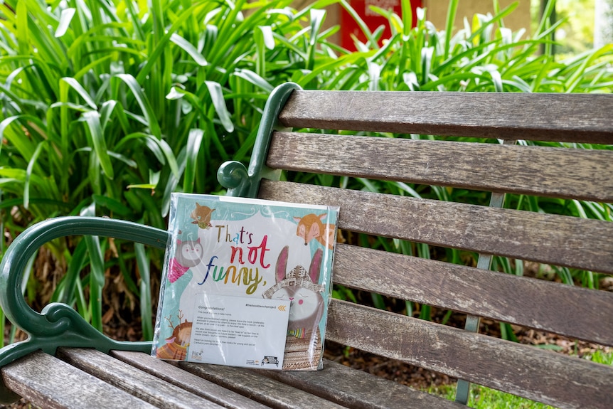 A book titled That's not funny sitting on a park bench