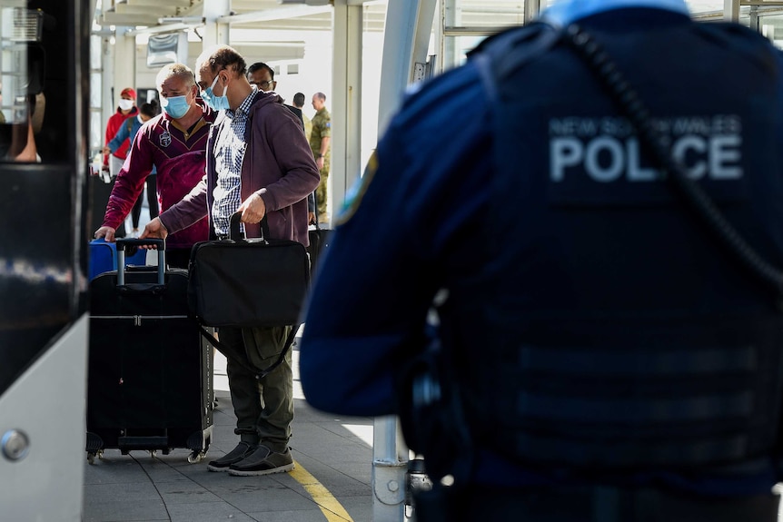 The back of a NSW Police officer, with people boarding a bus in the background.