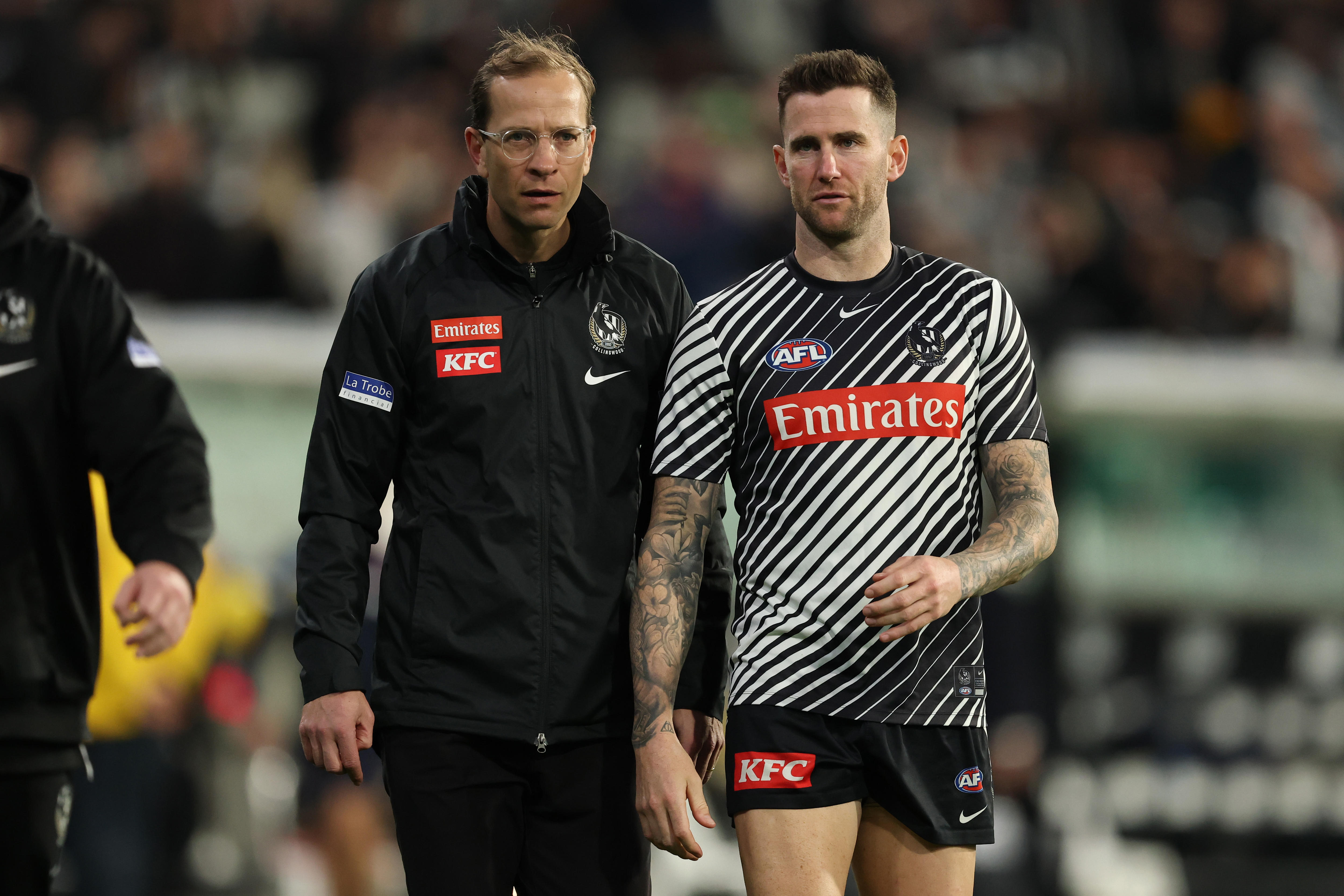 Jeremy Howe walks on the boundary with COllingwood Magpies official Charlie Gardiner.