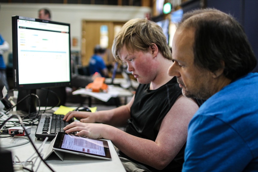 Koby, 14, with mentor, software engineer, Gary Barnes, building a website for the participants to share their work.