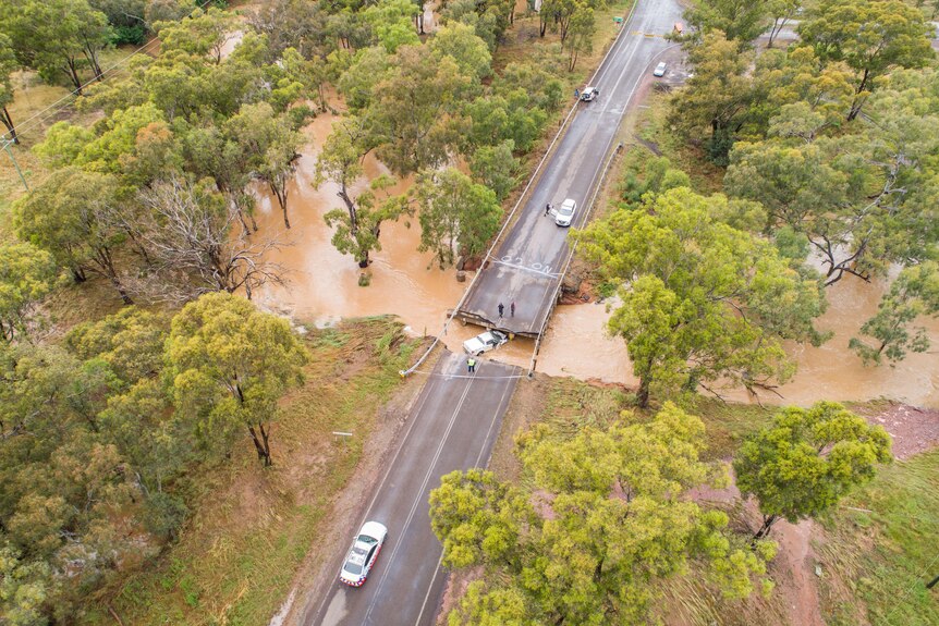 A vehicle in floodwater under a collapsed bridge.