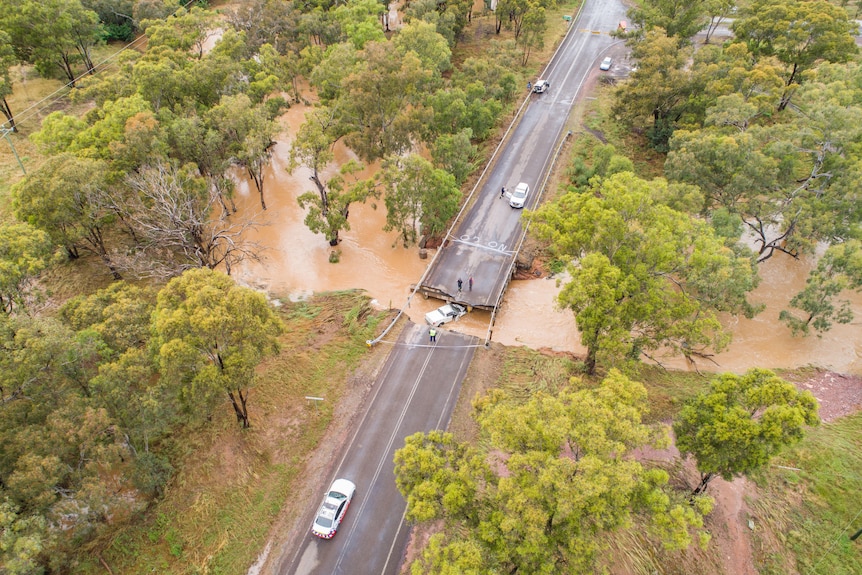 A vehicle in floodwater under a collapsed bridge.