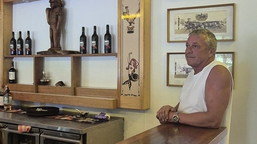 Man leaning on bar with Peninsula Hotel sign in background