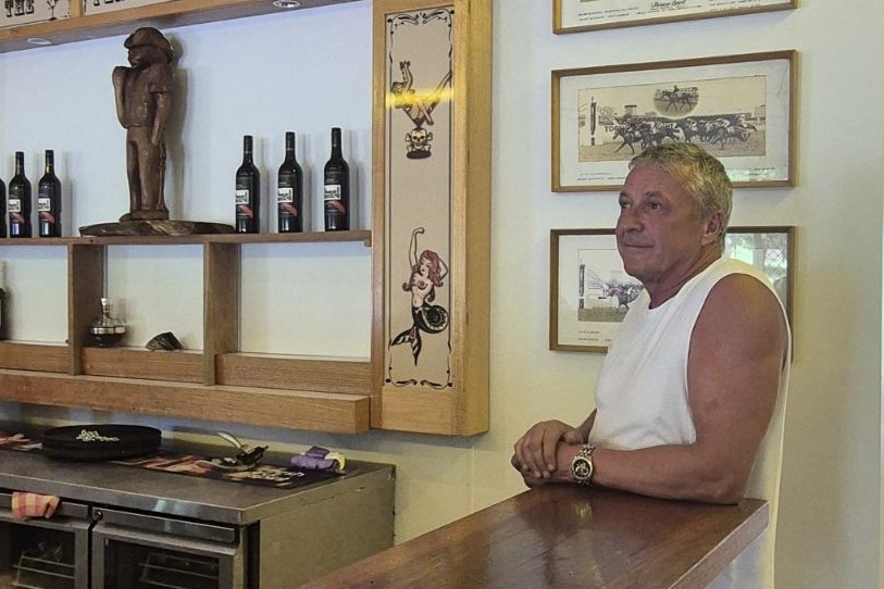 Man leaning on bar with Peninsula Hotel sign in background