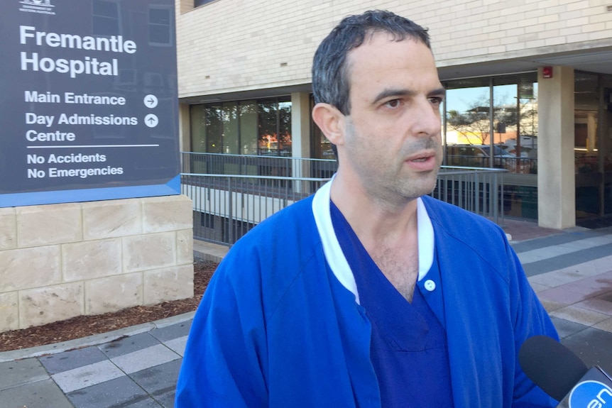Dr Omar Korshid wearing blue scrubs in front of the Fremantle Hospital sign.