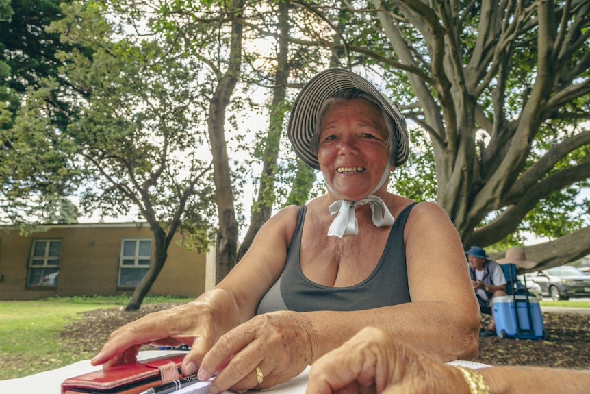 Ava sits in a hat at a table, smiling as she plays cards