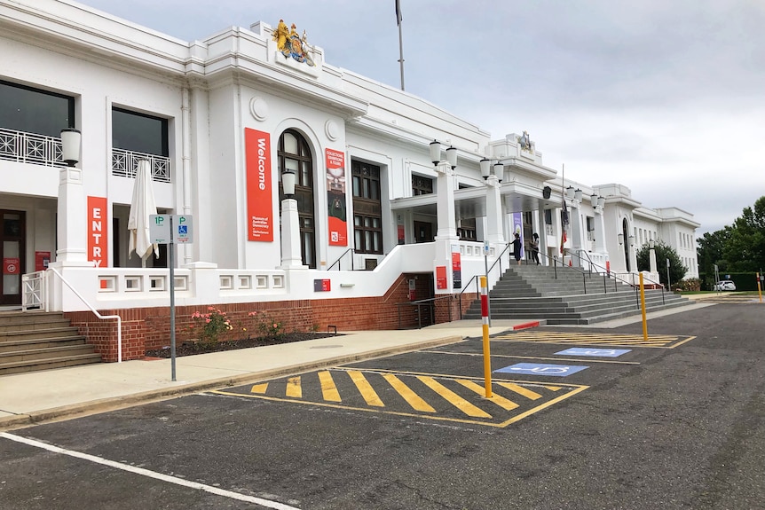 A white building with red signs and a car park