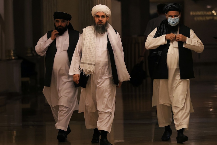 three men walking inside a hallway 